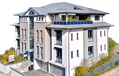 Außenansicht des Bürogebäudes der Steuerberatung Bruchhaus – modernes, mehrstöckiges Gebäude mit Balkonen, Glasfassade und gepflegtem Eingangsbereich.“