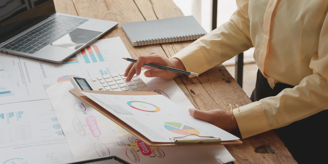 Close up of person looking at data and charts at a desk. 
