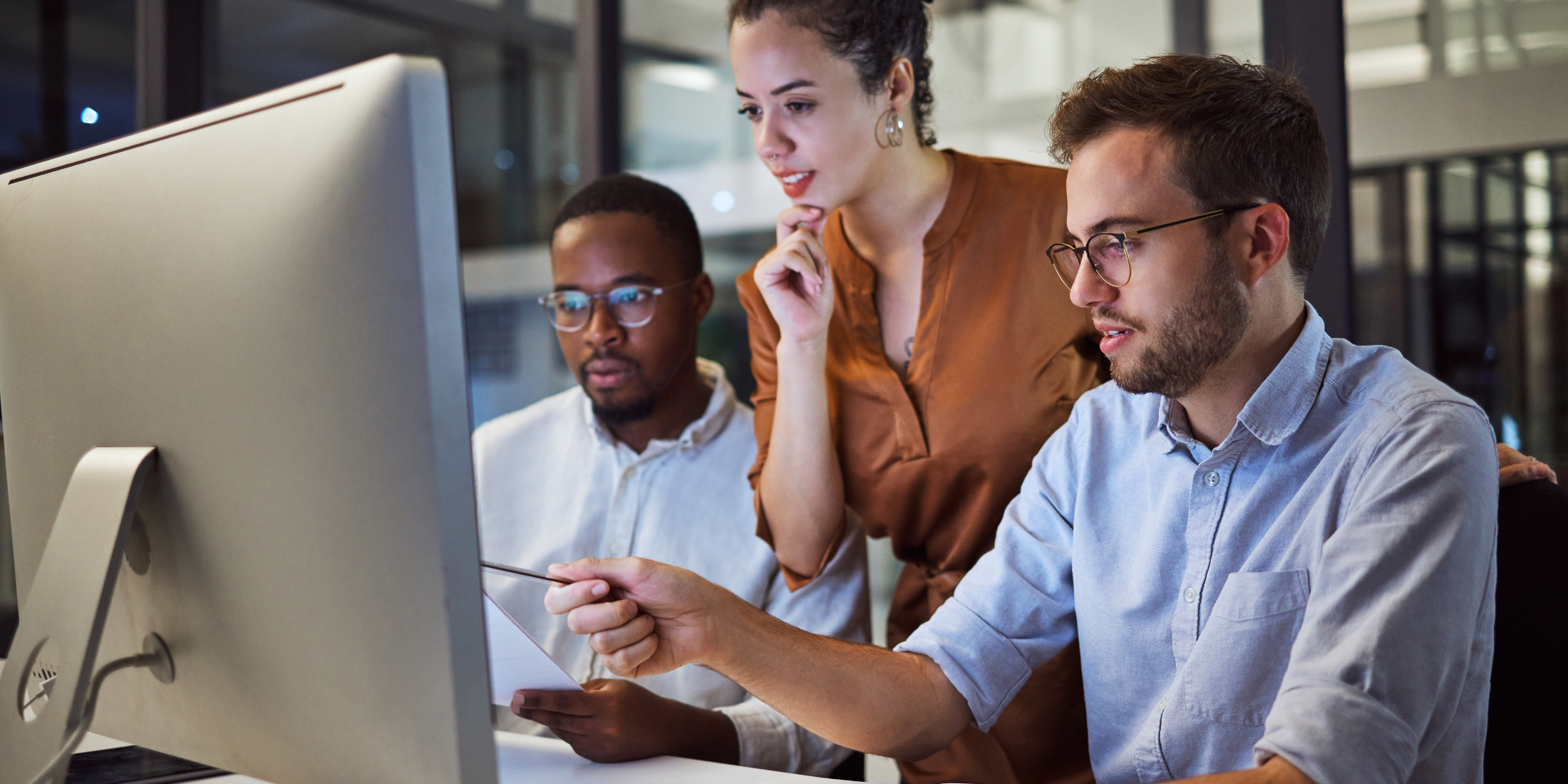 Two men and one woman looking at a computer screen.
