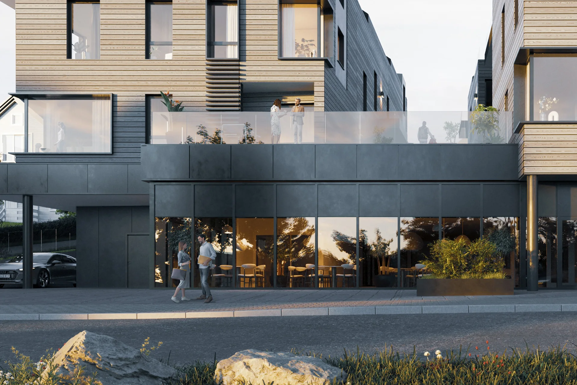 Næringsbygg i tre og mørk fasade med serveringslokale bak glassfront mot gaten
