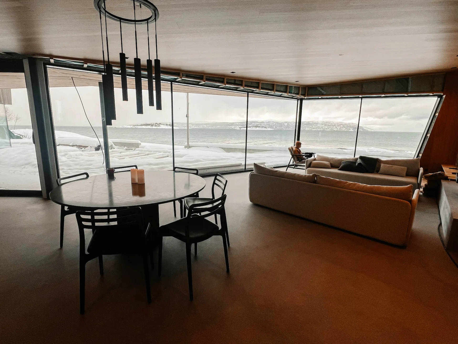 Lyst stue- og spiserom etter totalrenovering, med panoramavinduer mot snødekt fjord