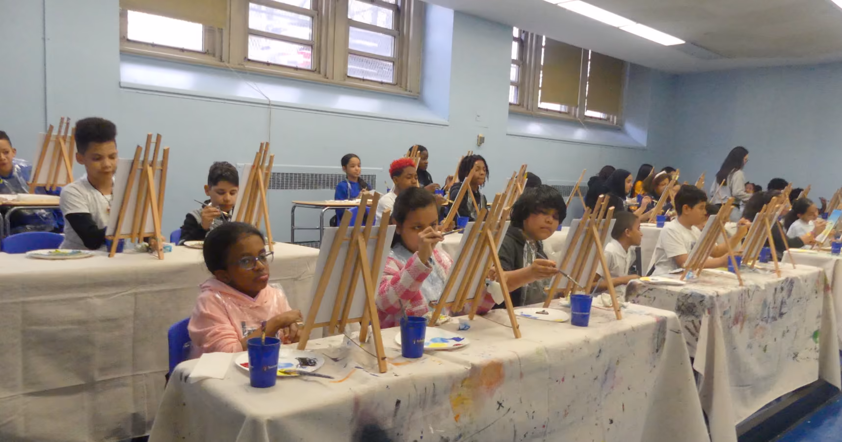 Students painting on easels during a school art class activity