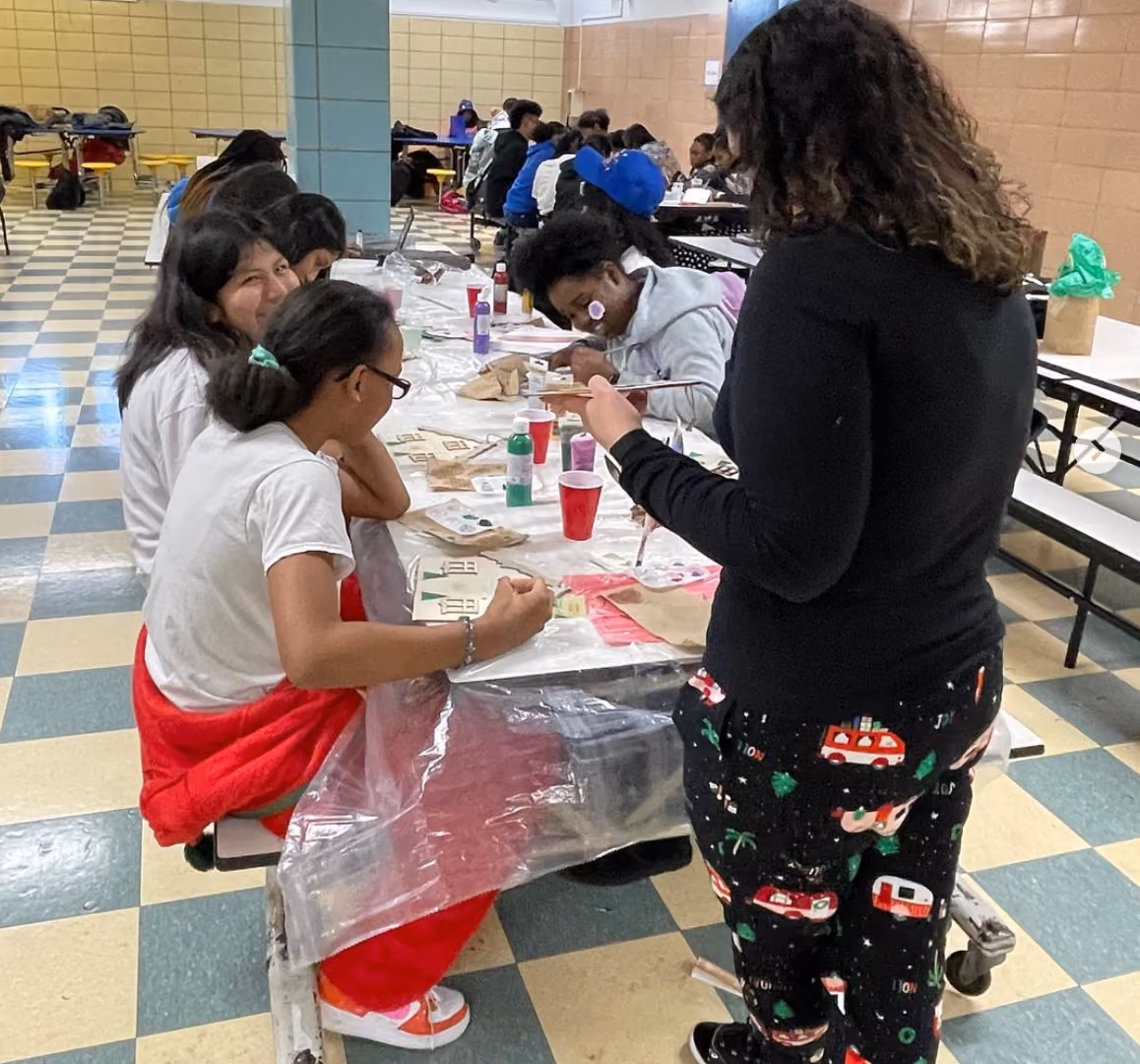 Students painting wooden crafts together at a school cafeteria art activity