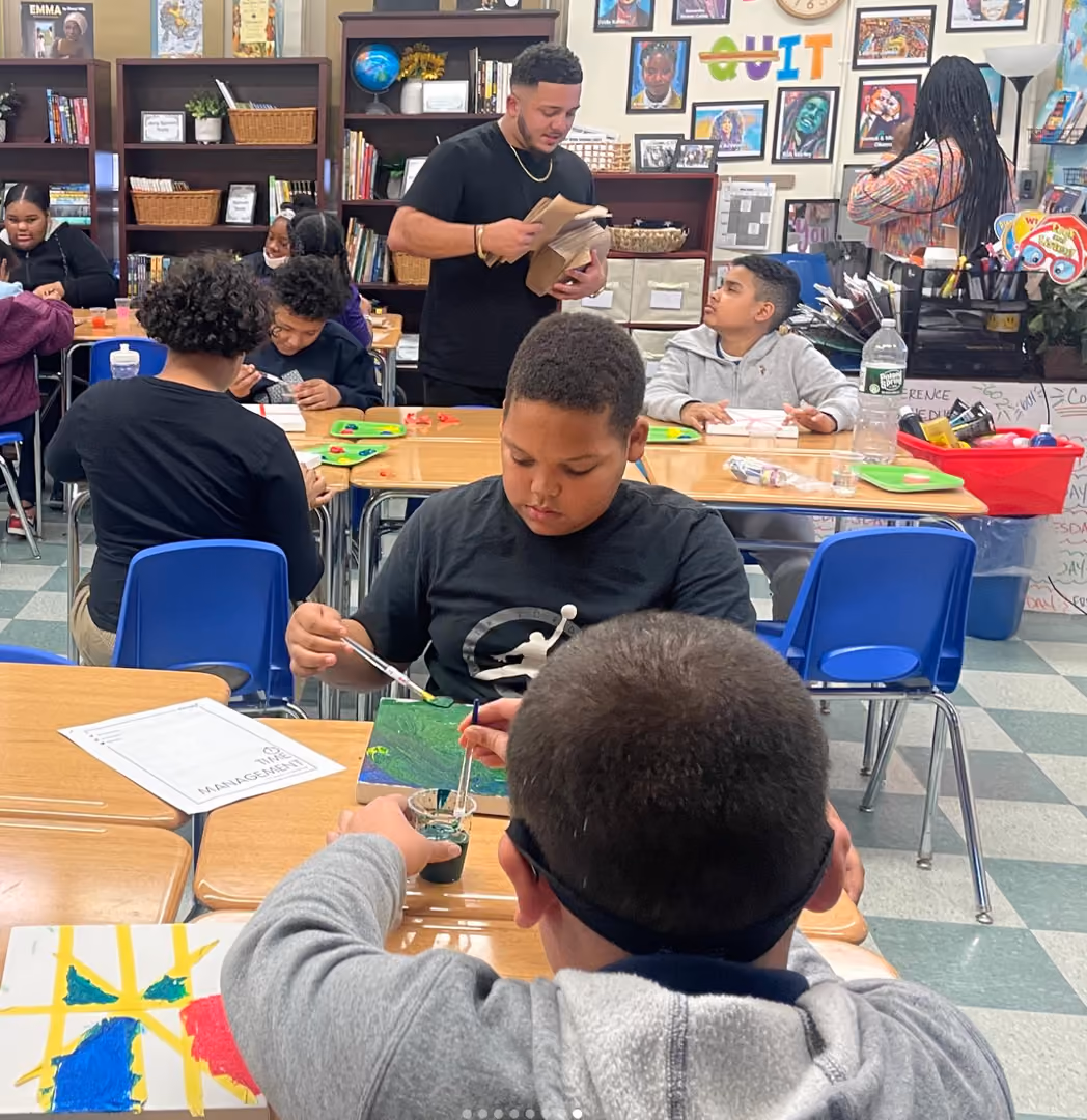 Students painting on canvas during a classroom art activity