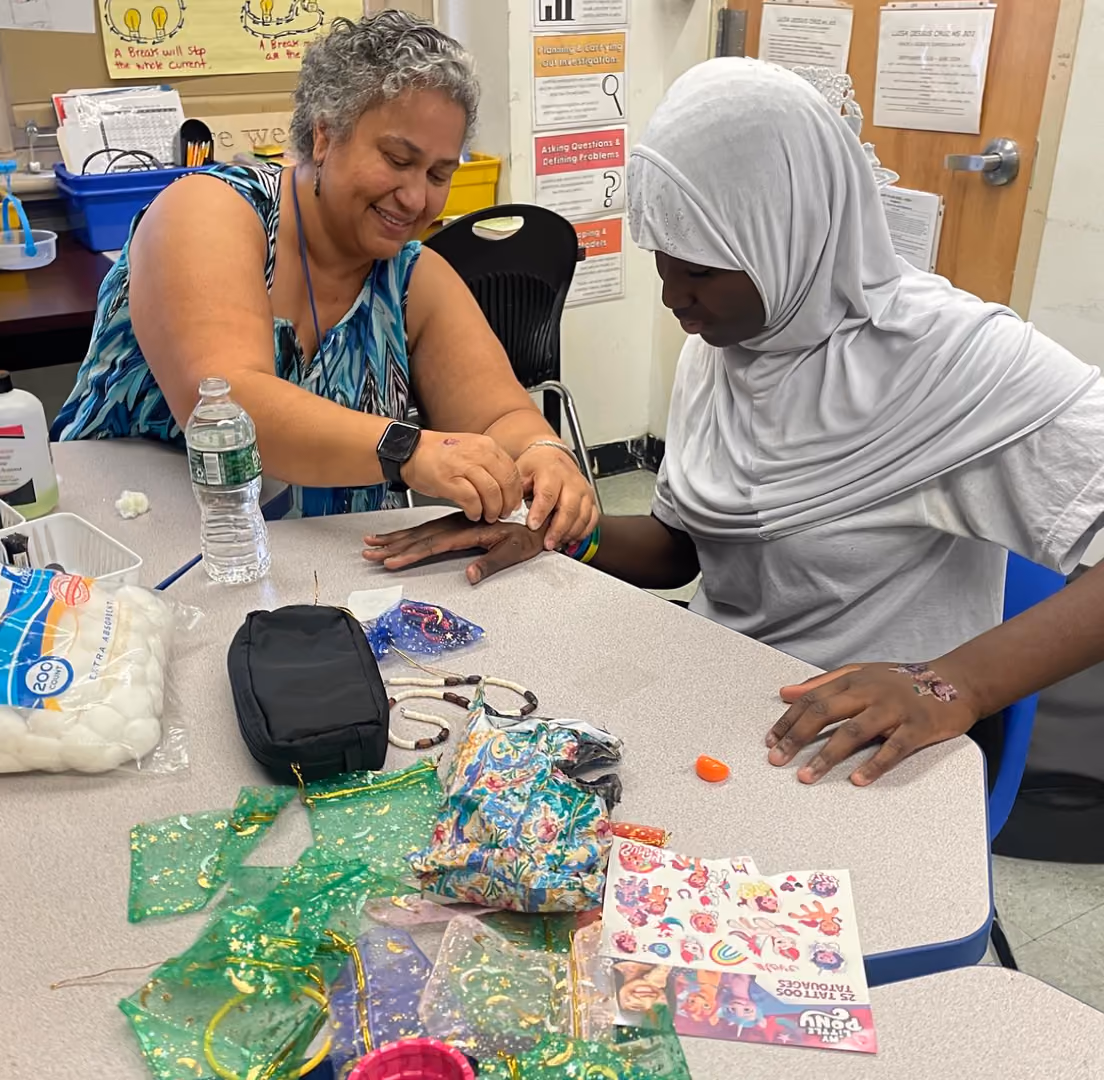 Teacher and student working together on a craft activity at a classroom table