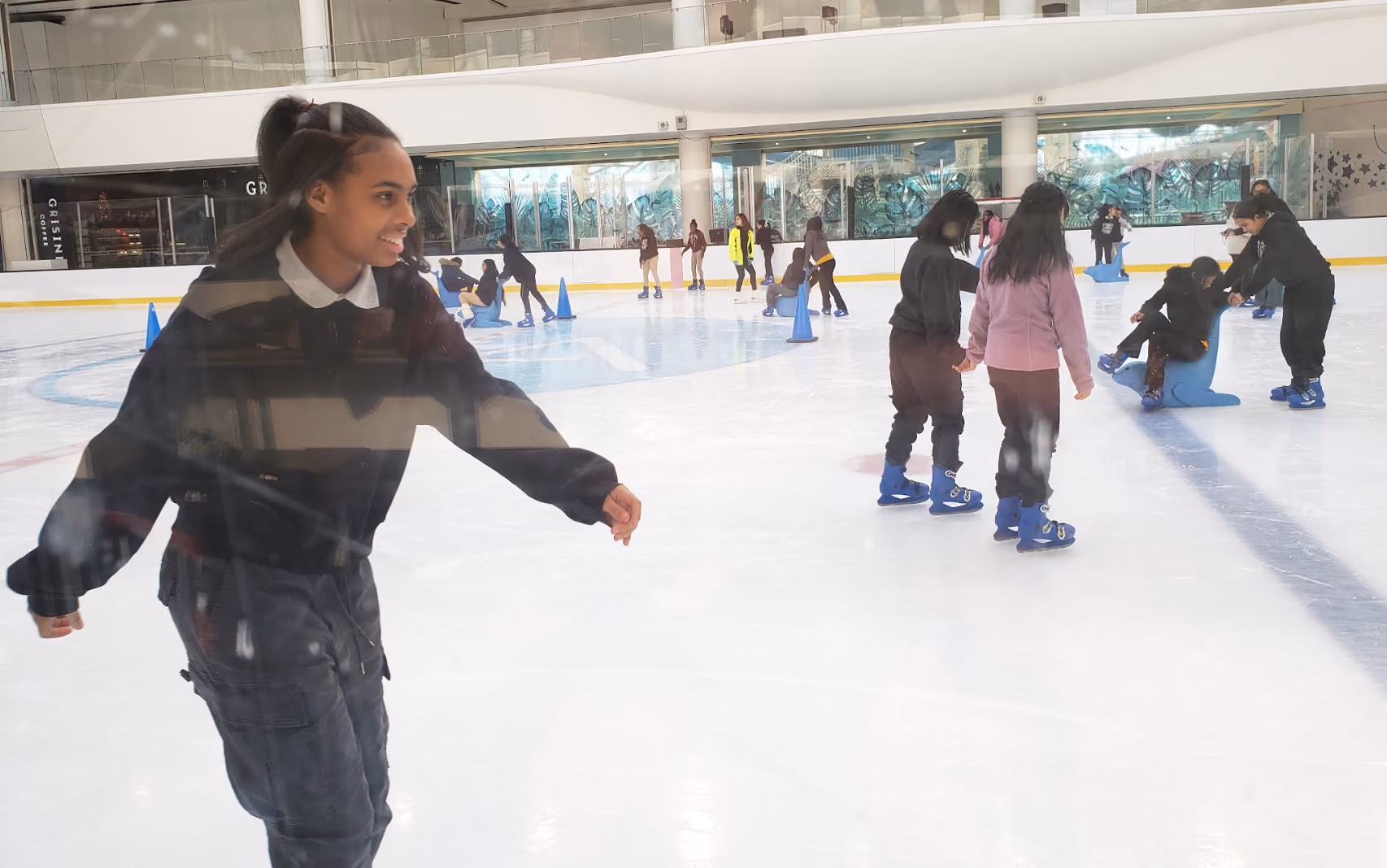 Students ice skating together on an indoor rink during a school trip