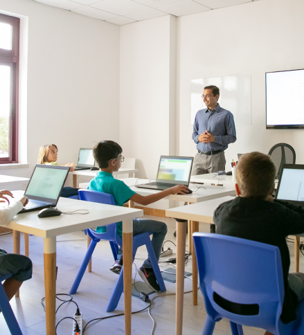 Teacher leading a computer class with students on laptops