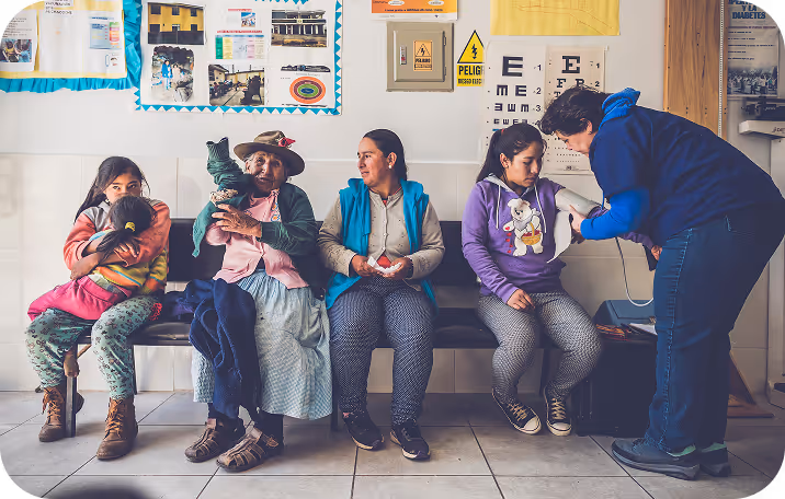A group of people waiting in a line of chairs in a doctors office.