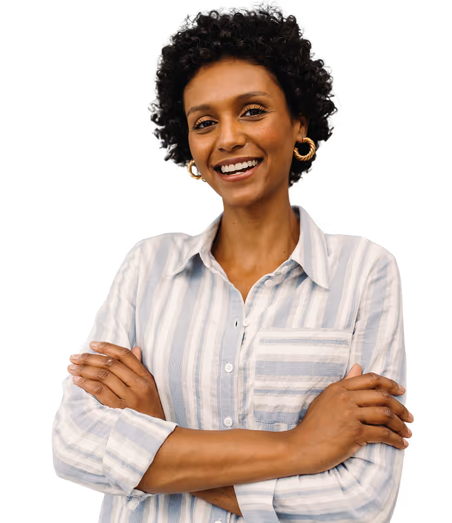 Mulher sorridente com cabelos cacheados curtos, usando blusa listrada e brincos de argola dourados, com braços cruzados.