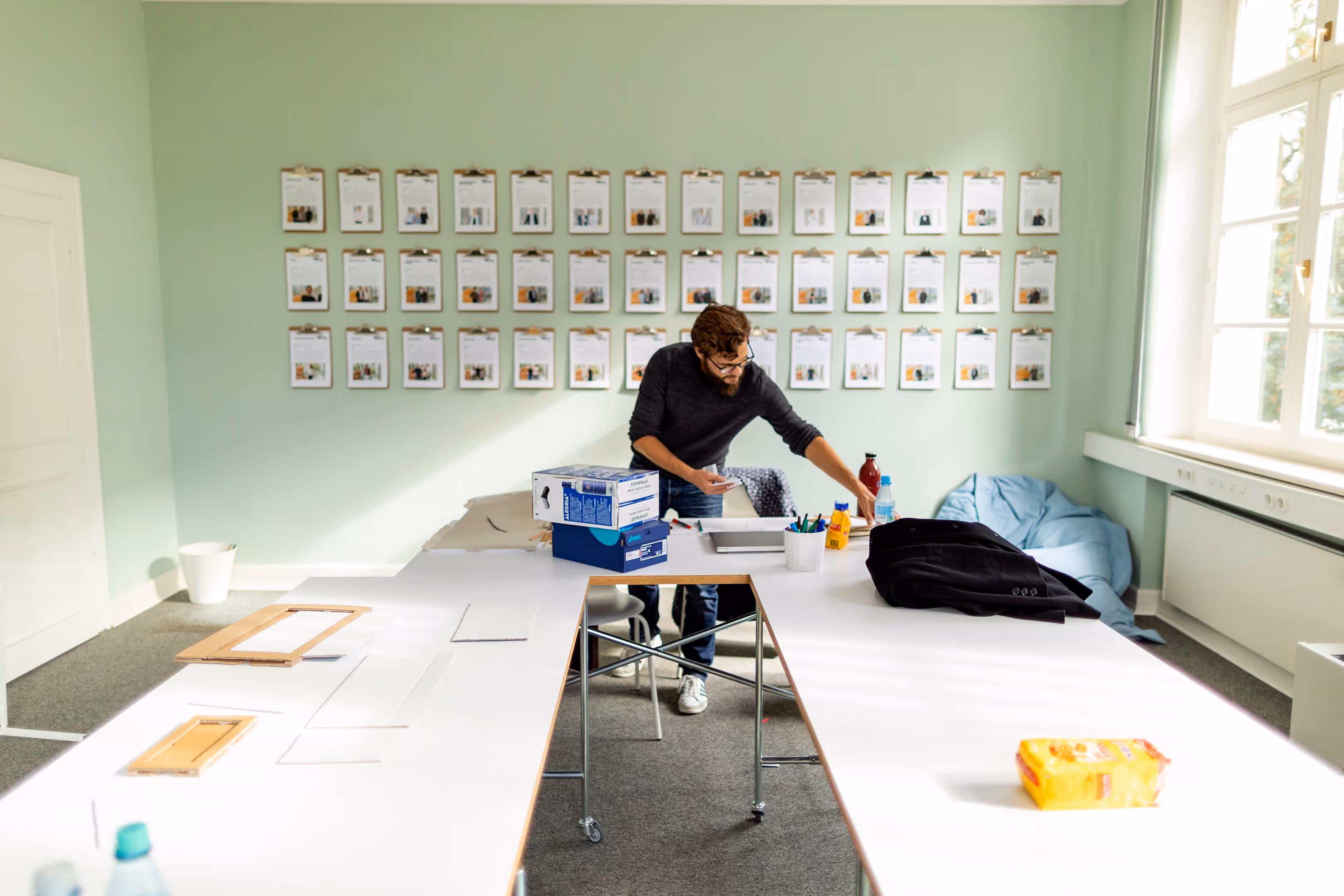 Ein Gründer arbeitet in der Villa Anthropia in einem Raum, in dem an den Wänden Steckbriefe der Startups hängen.