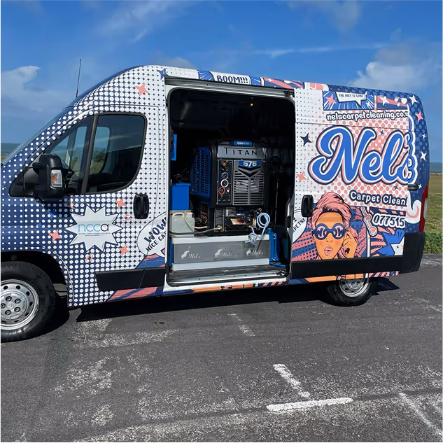 Colourful carpet cleaning van with open side door showing cleaning equipment inside on a sunny day.