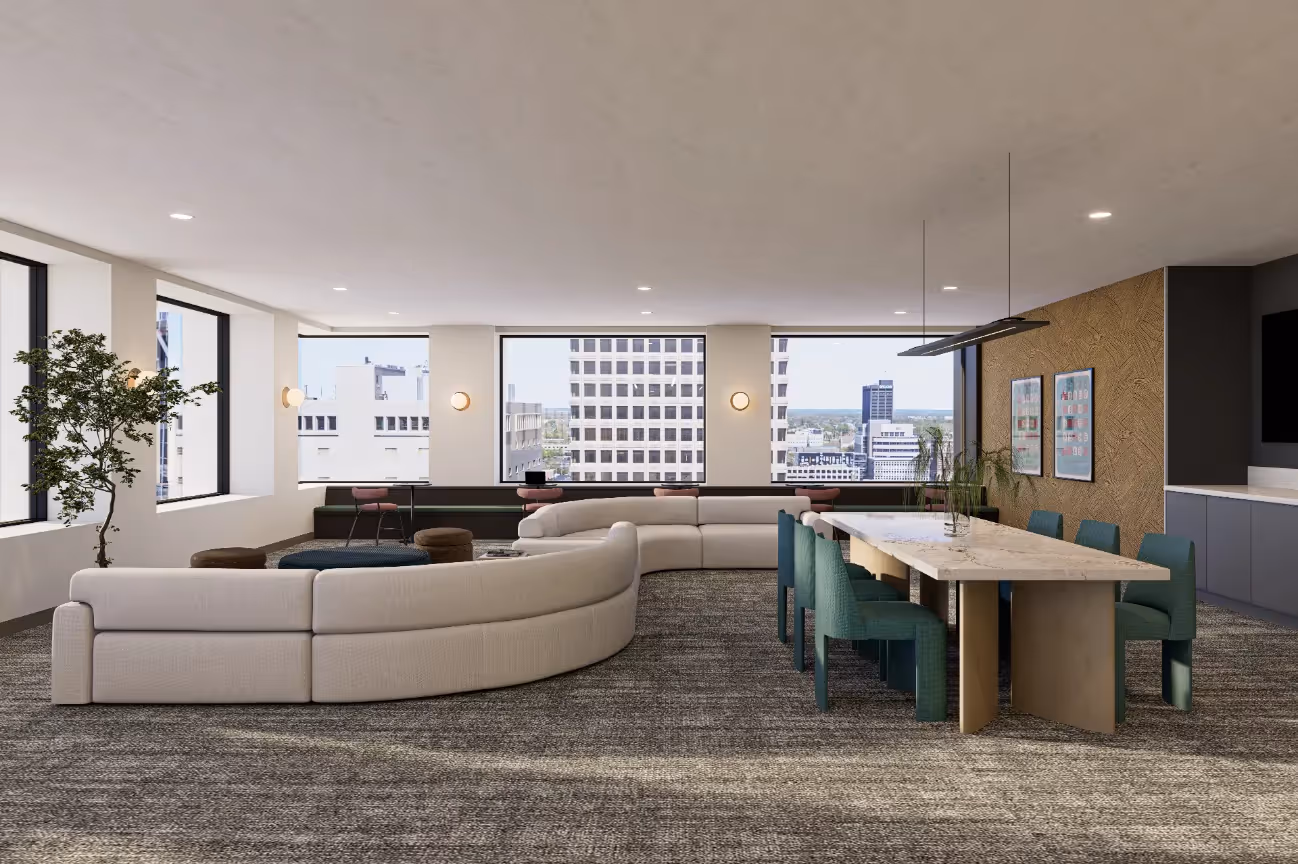 Modern resident common area featuring a curved sofa, long dining table, and large windows overlooking the city, at Continental Tower in Columbus, Ohio.