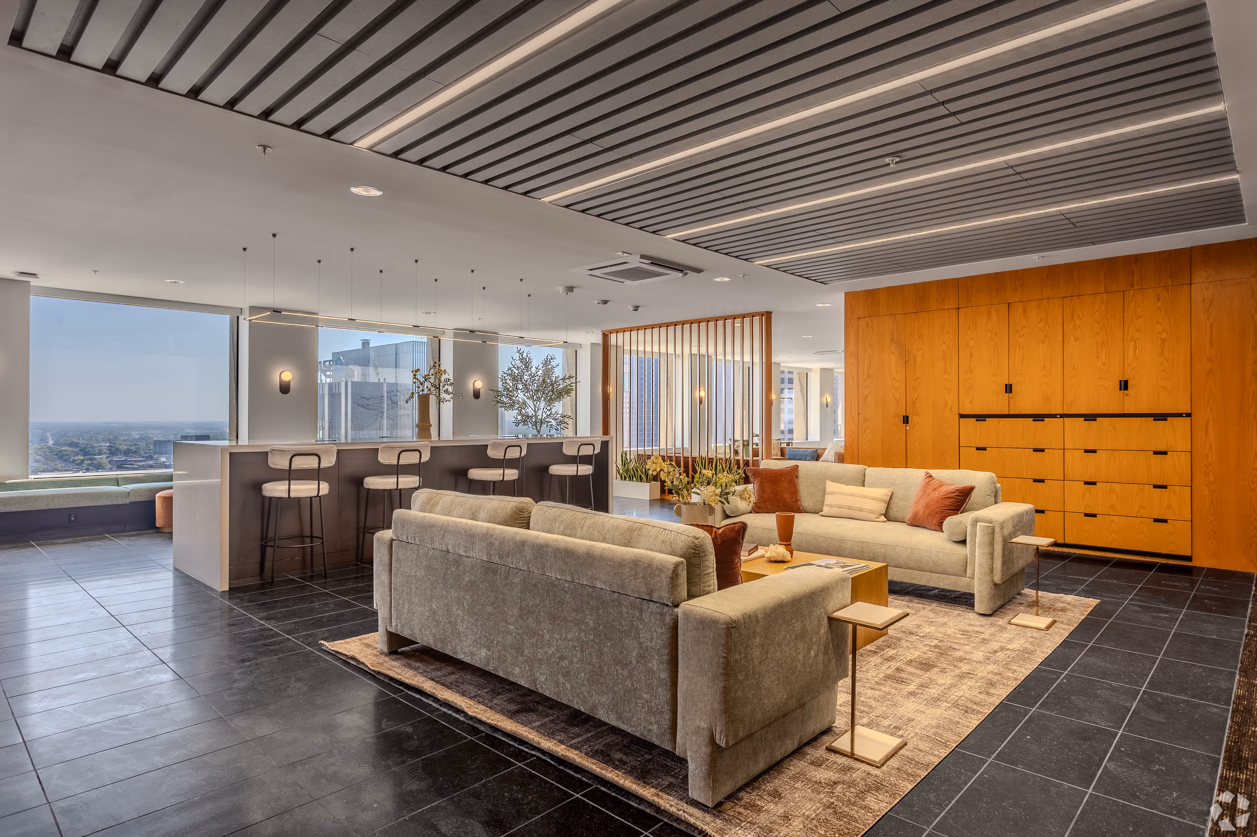 Modern resident common area featuring a curved sofa, long dining table, and large windows overlooking the city, at Continental Tower in Columbus, Ohio.