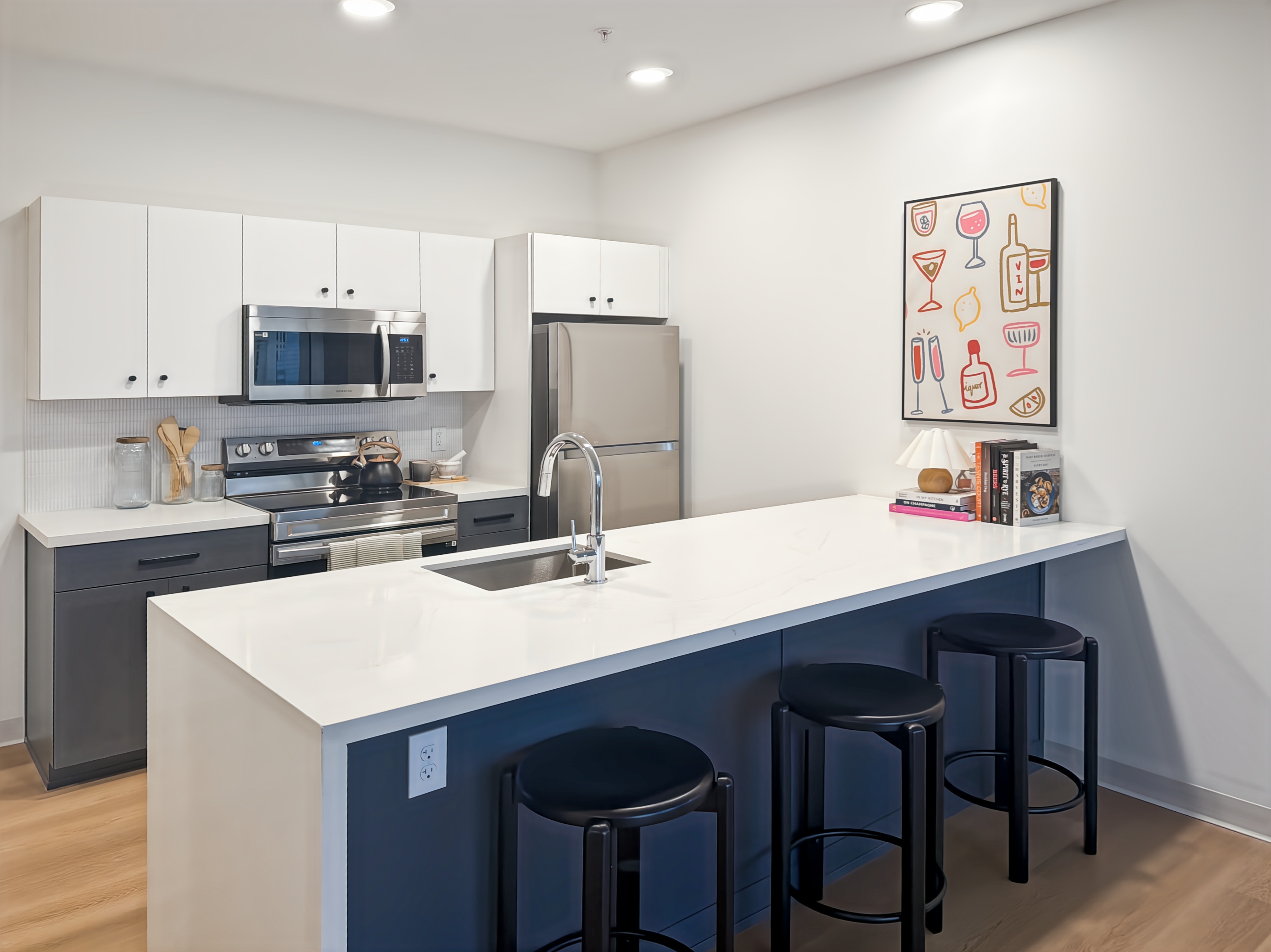 Contemporary kitchen with a large island, blue and white cabinetry, and stainless steel appliances, typical of apartments at Continental Tower in Columbus, Ohio.