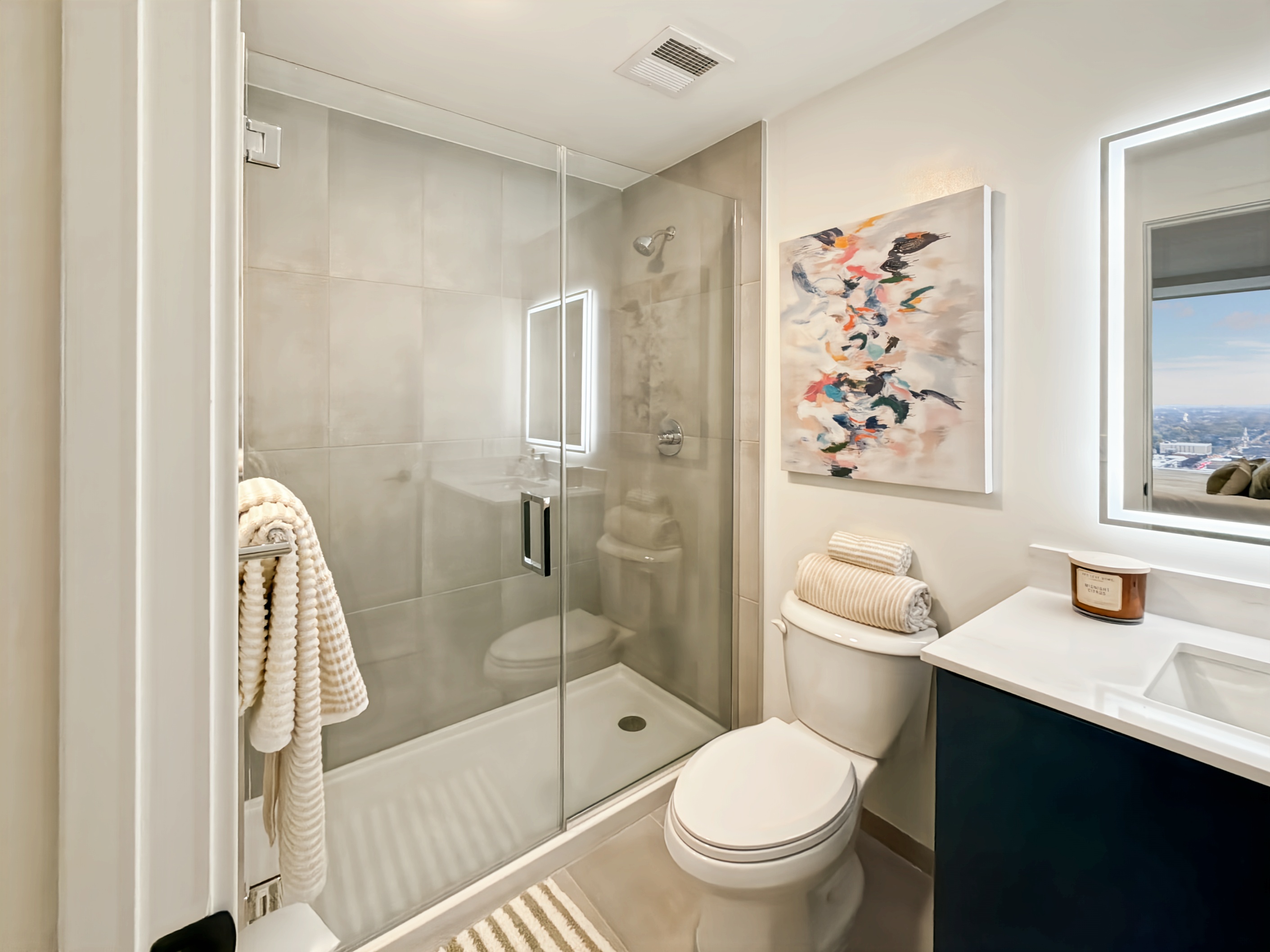 Modern bathroom with a spacious vanity, illuminated mirror, walk-in shower, and contemporary design at Continental Tower in Columbus, Ohio.