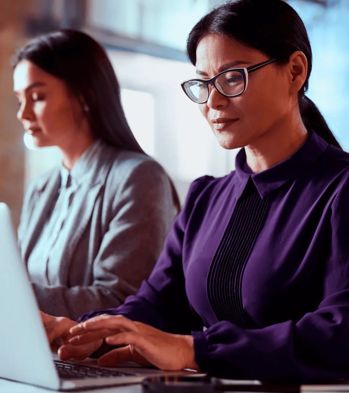 Duas mulheres trabalhando no escritório olhando para o computador.