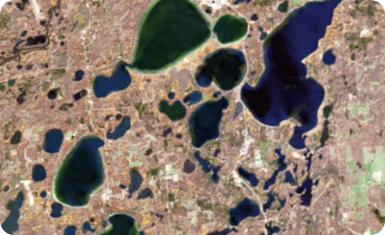 An aerial view shows a vast landscape with multiple bodies of water of varying sizes.