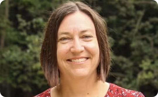 A close-up photograph of Professor Kendra Spence Cheruvelil smiling, framed by a soft-focus backdrop of foliage.