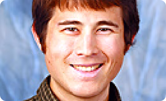 A close-up photograph of a smiling human face, framed by a clear backdrop.