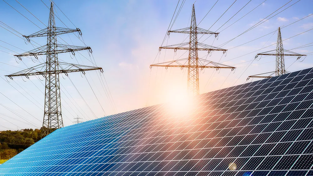 Solar panels with electricity transmission towers in the background