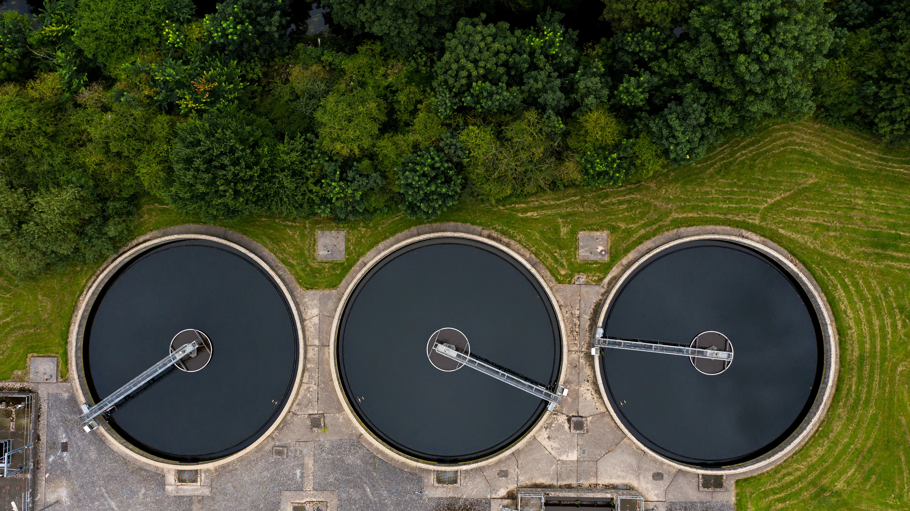 Aerial view of circular water treatment tanks surrounded by trees