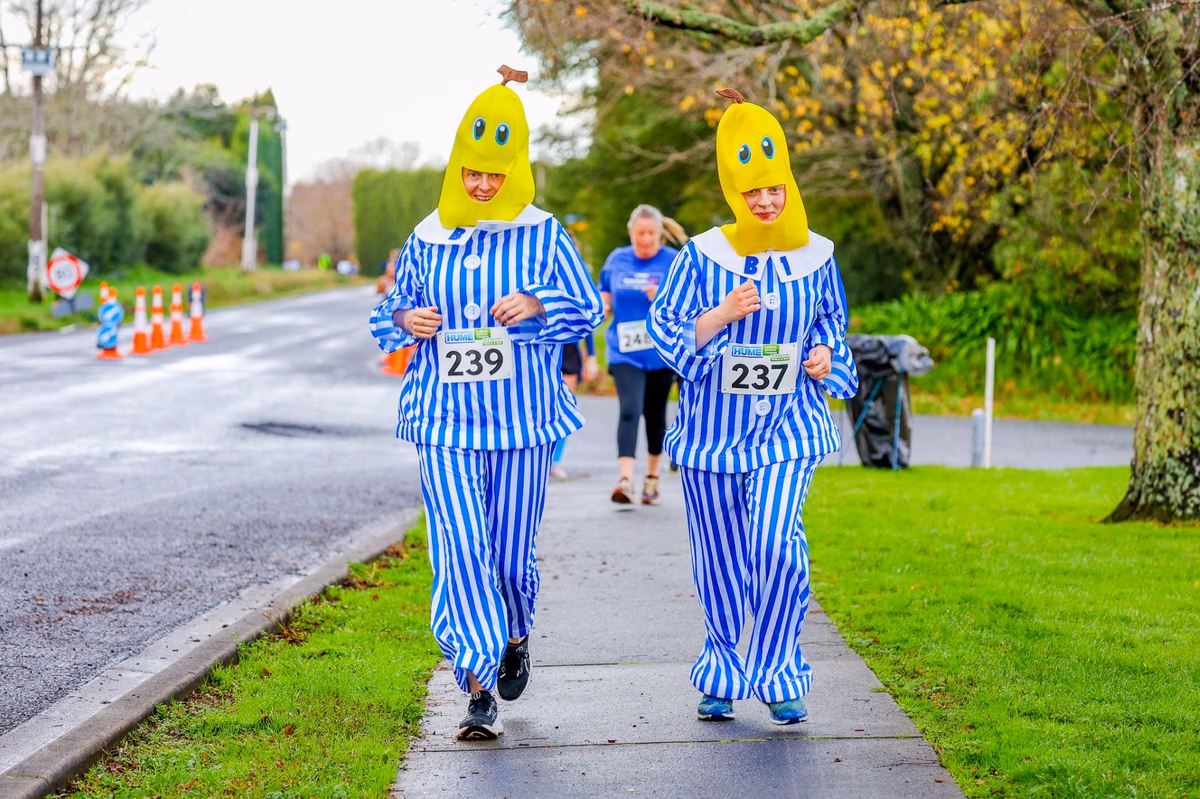 Two participants in Bananas in Pyjamas costumes jogging along a footpath during a fun run event