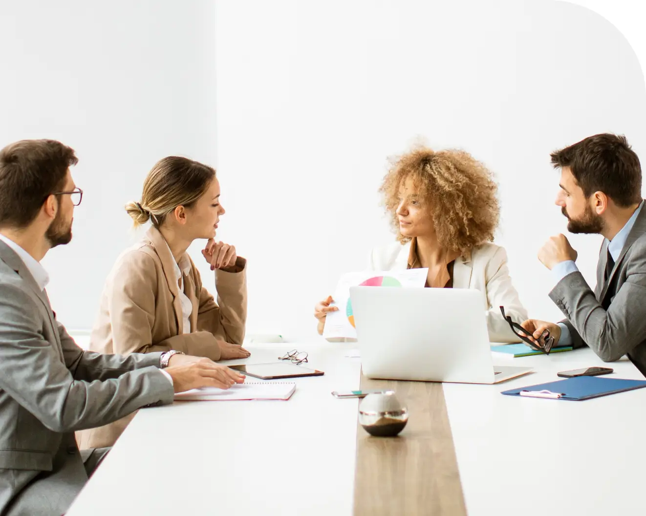 Four people in a business meeting discussing documents around a conference table