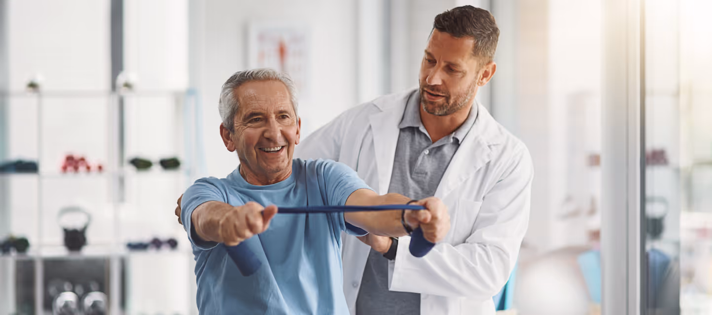 Older man using a resistance band with therapist’s guidance.
