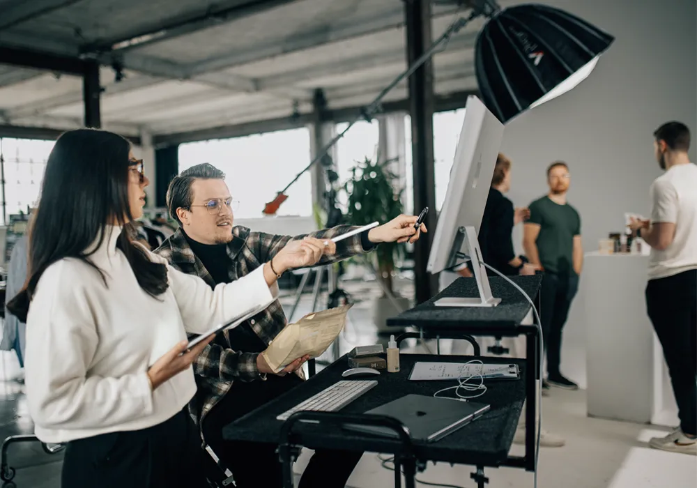 A man and woman in a room with a computer and a camera.