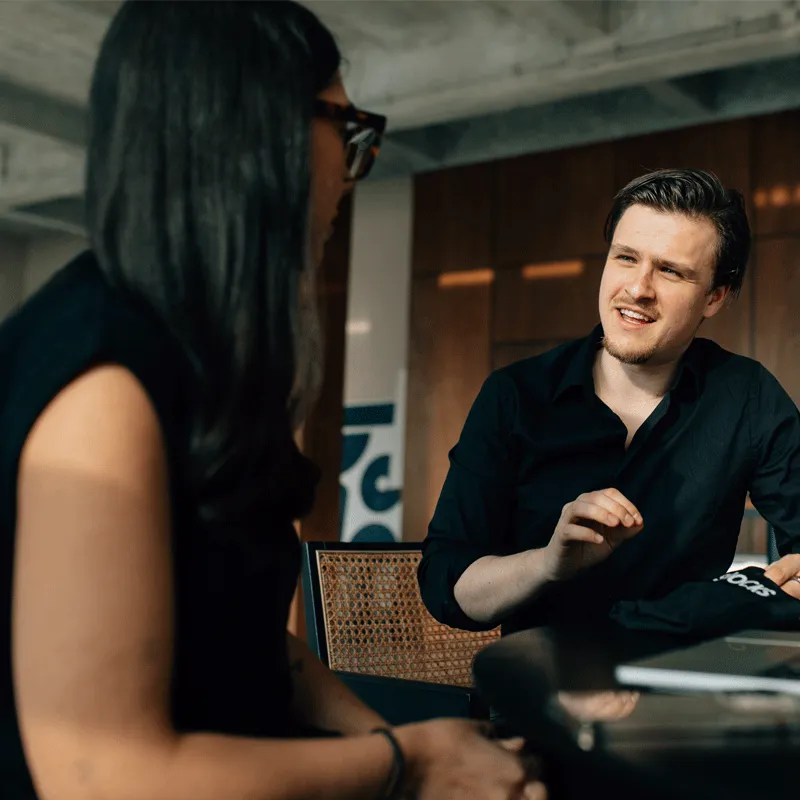 A man in a black shirt is talking to a woman.