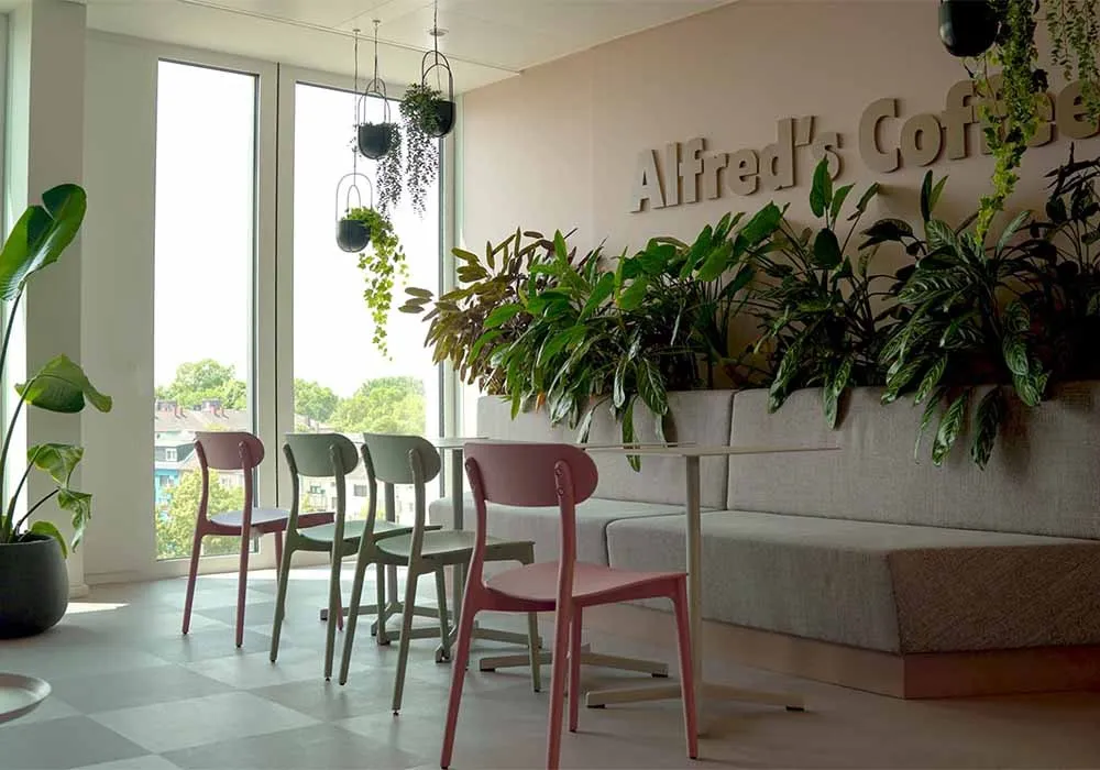 A room with a pink bench and green chairs.