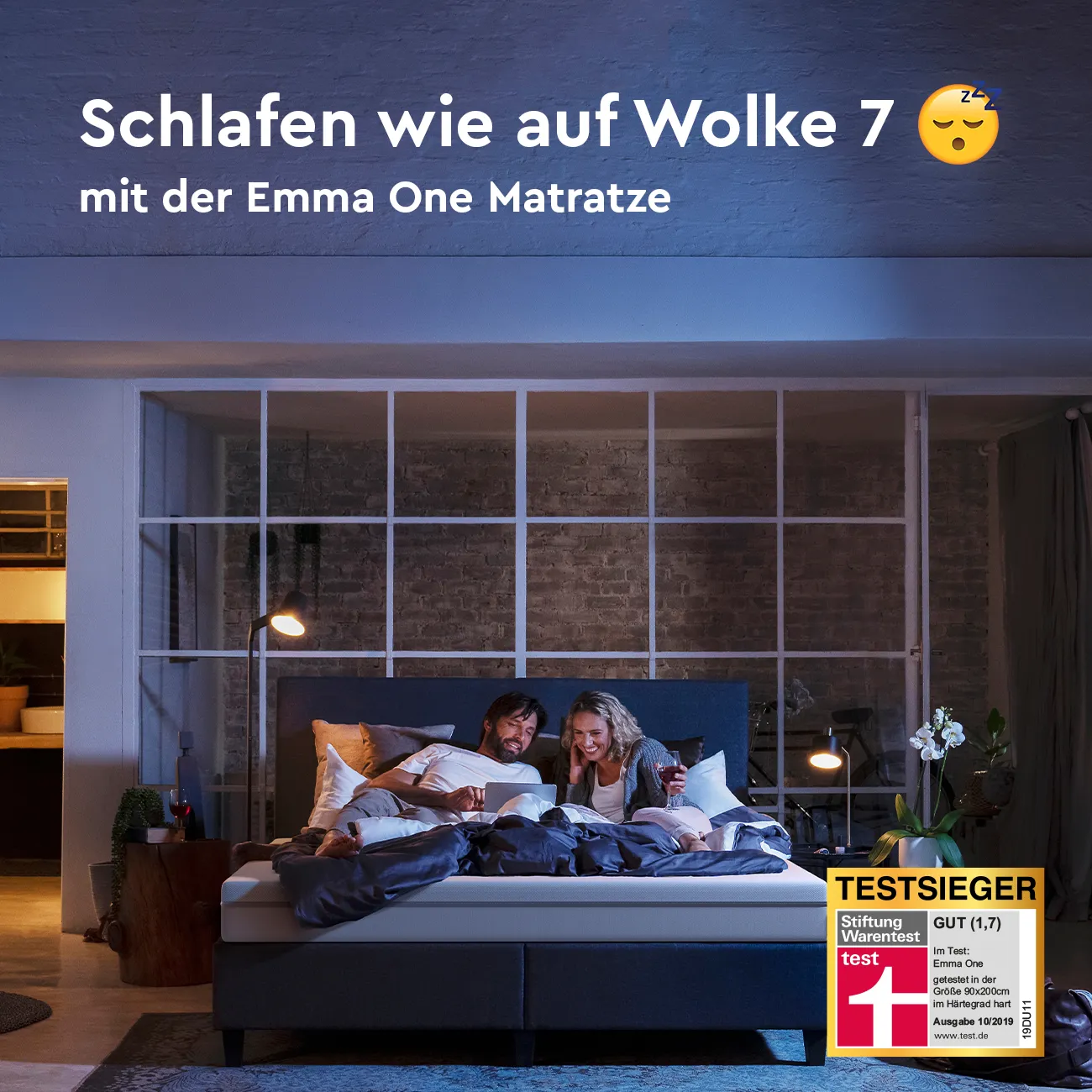A man and woman laying in bed with a poster that says "Schlafen wie ein Einhorn" above them.
