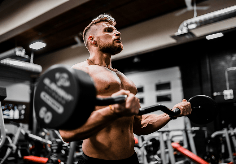 A man doing bicep curls with a barbell at a gym