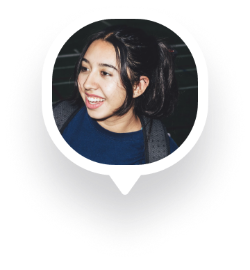 Smiling woman with dark hair in a ponytail wearing a blue top and backpack looking to the side.