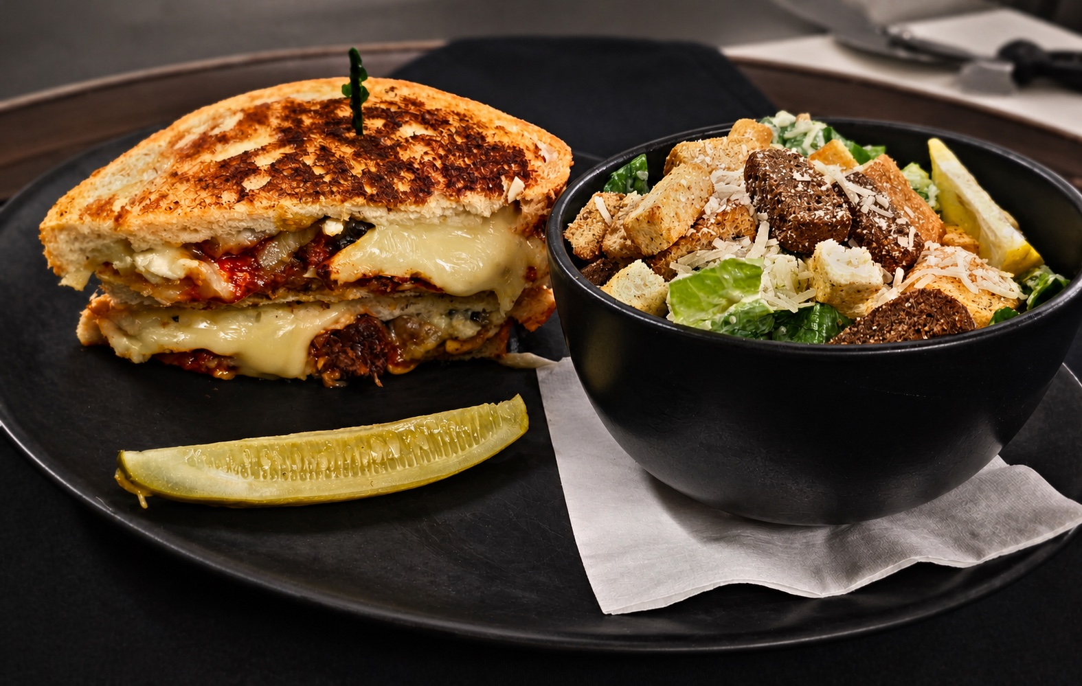 Brisket grilled cheese on sourdough with a side Caesar salad and pickle spear