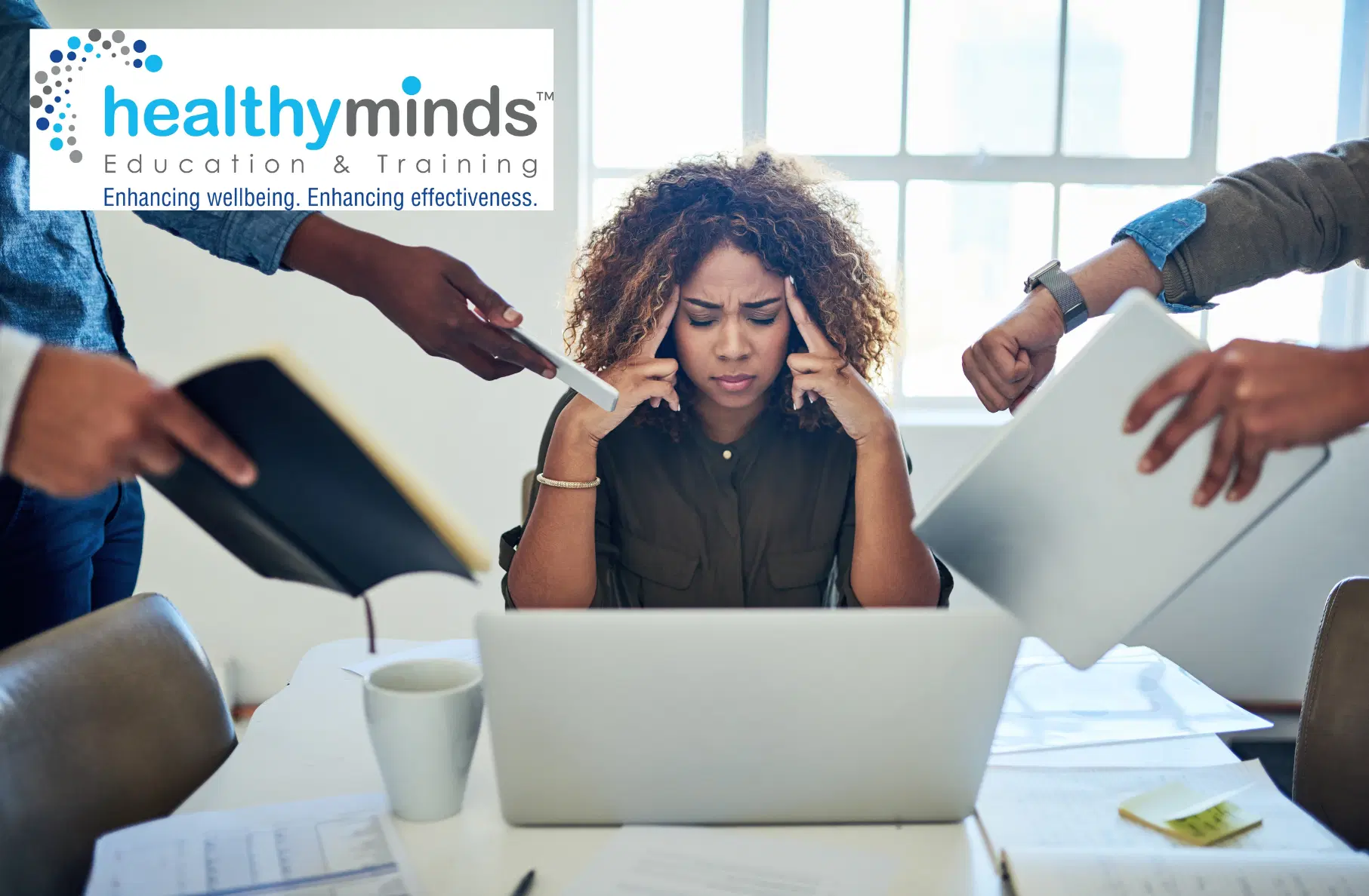 Stressed woman sitting at a desk with a laptop, holding her temples while multiple hands around her present work and documents.