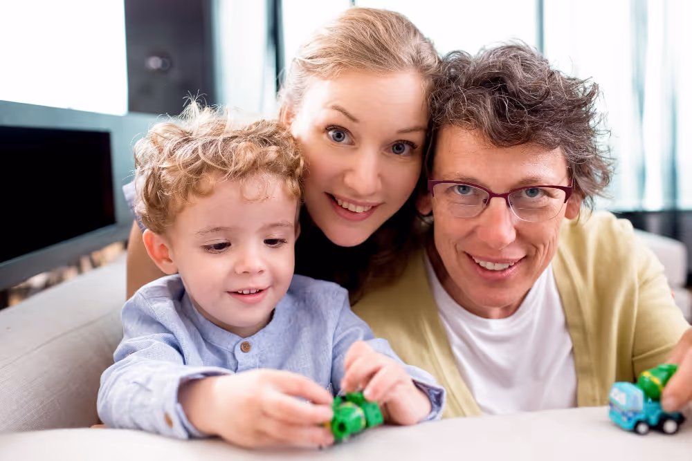 Smiling family with young child playing with toy cars together