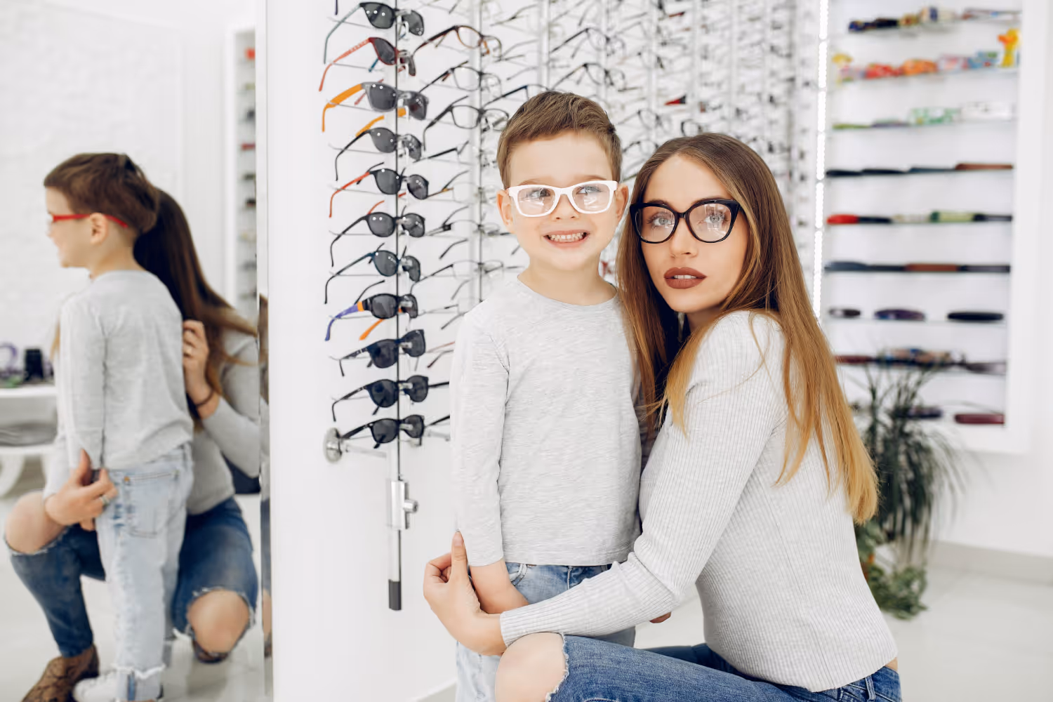 Mother and child trying on glasses in an optical store with eyewear display