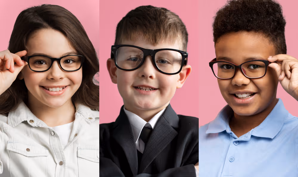 Three children in glasses smiling against pink background