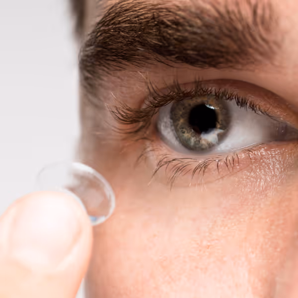 Close-up of an eye with a contact lens being carefully inserted