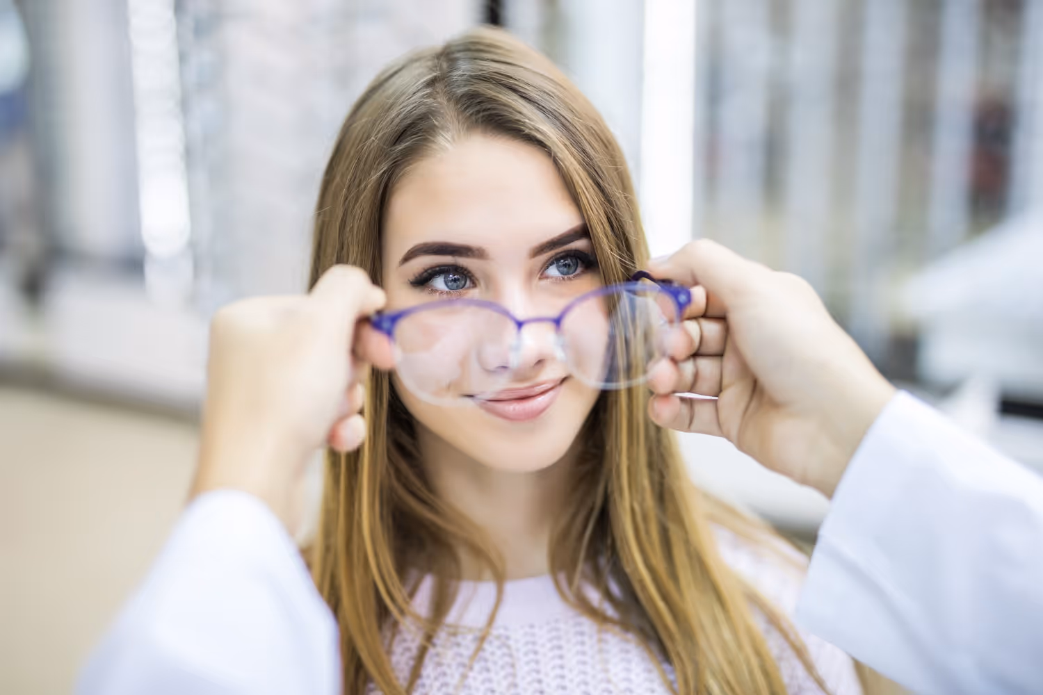 Woman holding purple glasses, smiling with blurred background