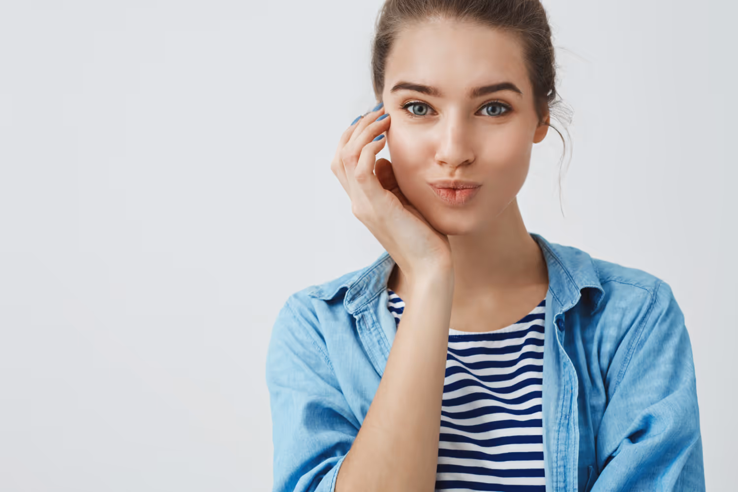 Woman in blue denim shirt and striped top posing thoughtfully