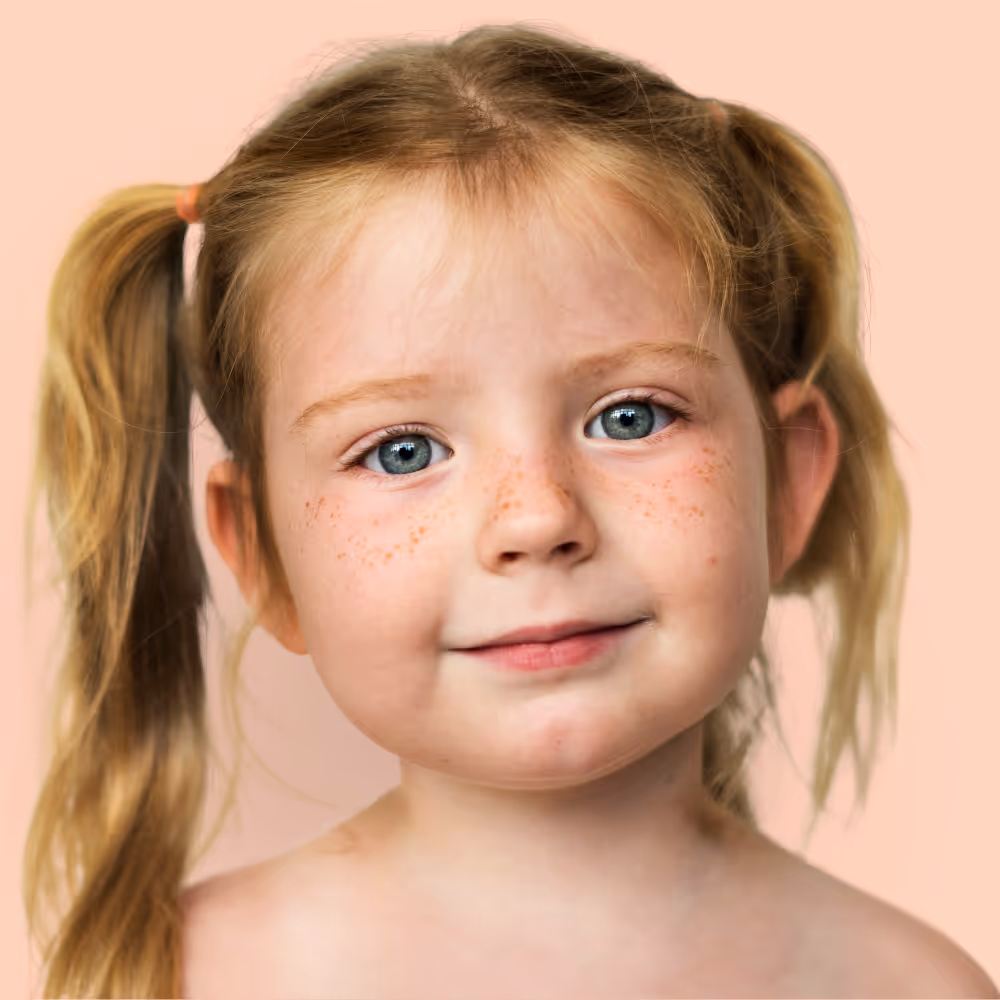 Young child with blue eyes and freckles in pigtails smiling