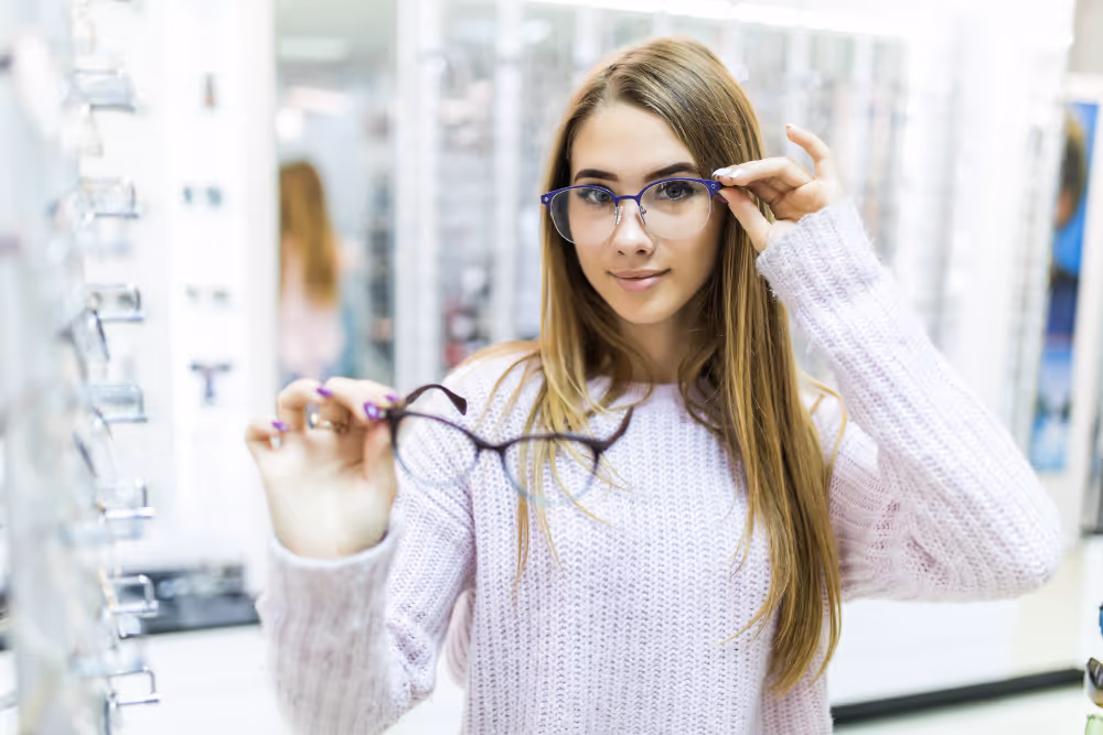 Woman trying on stylish purple glasses in optical store display