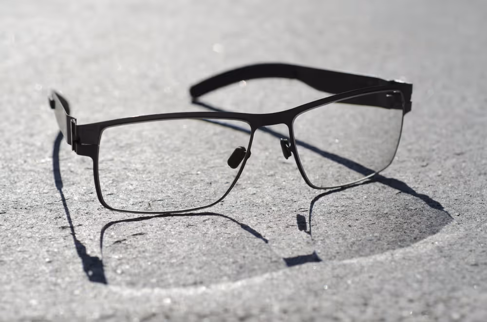 Black-framed glasses casting shadows on a textured gray surface