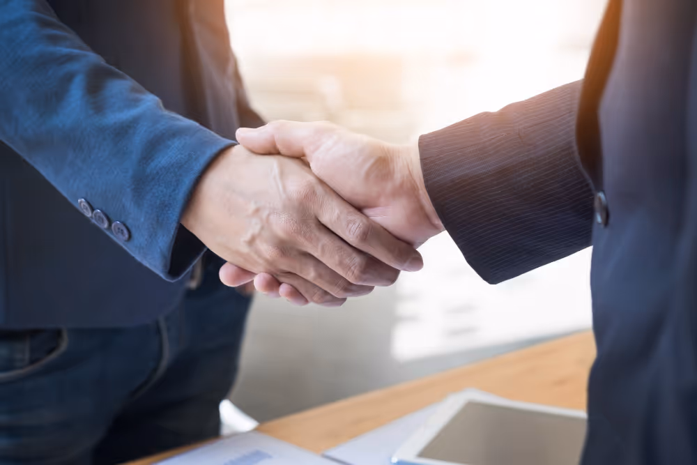 Two businesspeople shaking hands in professional meeting, confirming agreement