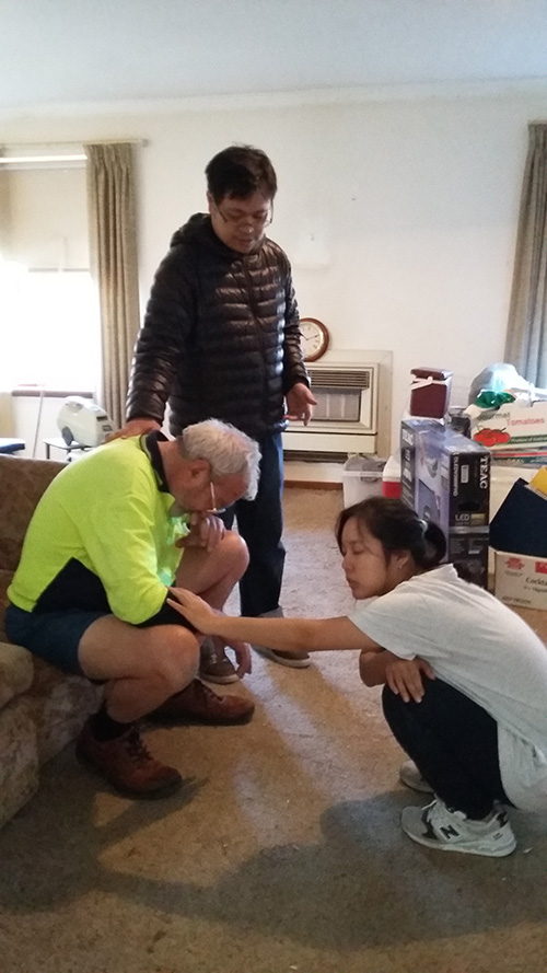 ARMS Ministry team members from YWAM Perth praying with a homeowner after helping with household repairs.