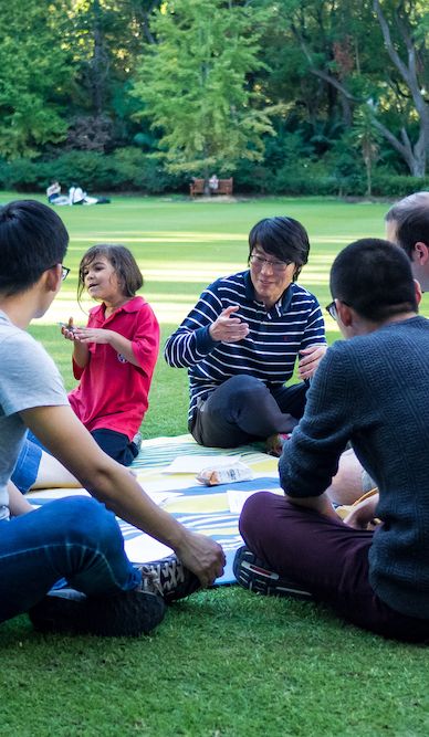 Frontiers Ministry volunteers and international students sharing stories and meals together in a park.
