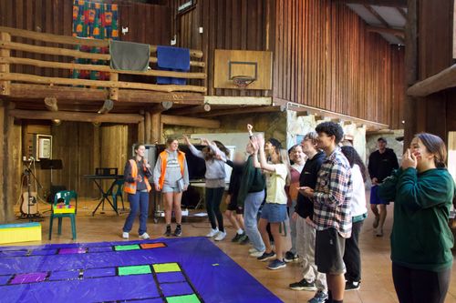Youth cheer and laugh indoors during a colourful team-building game at YWAM Perth Winter Camp