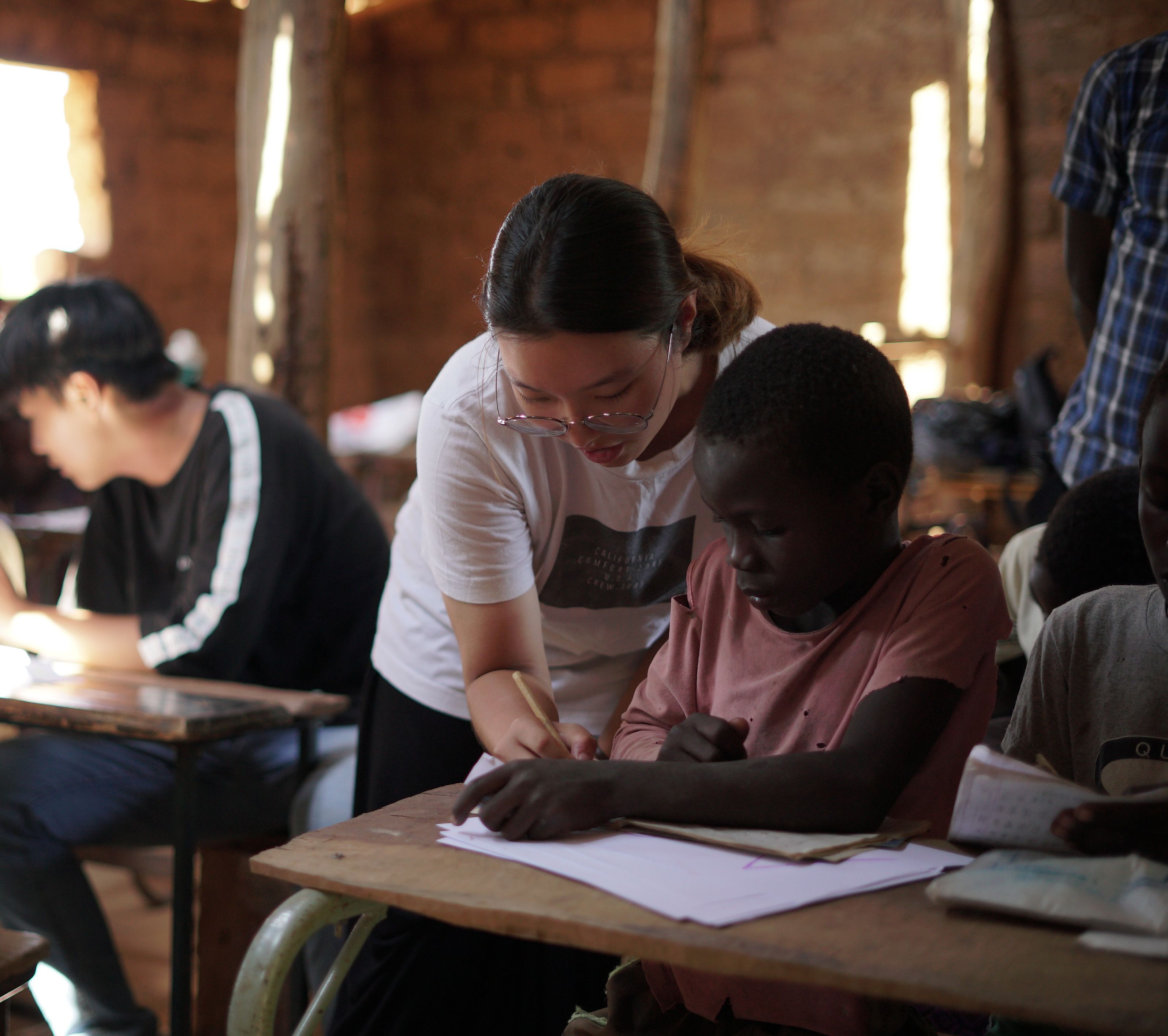 a teacher assists a student in a rustic classroom